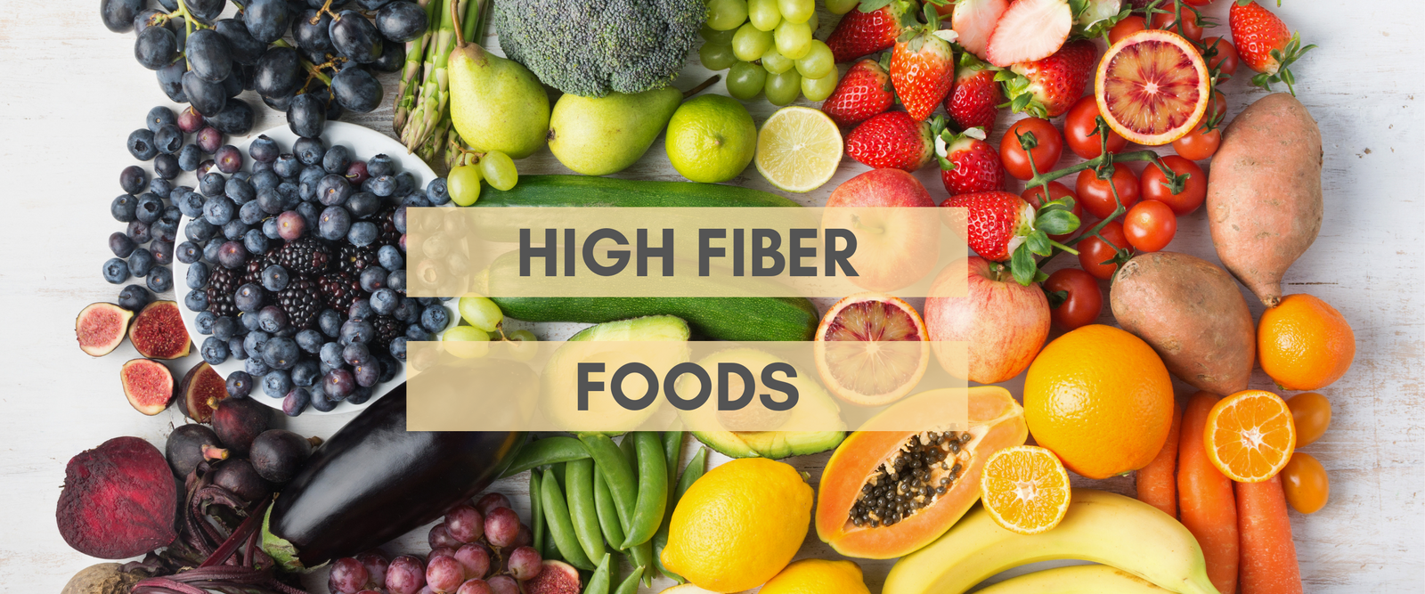 top view of different types of high fiber of fruits and vegetables on top of a wooden white table