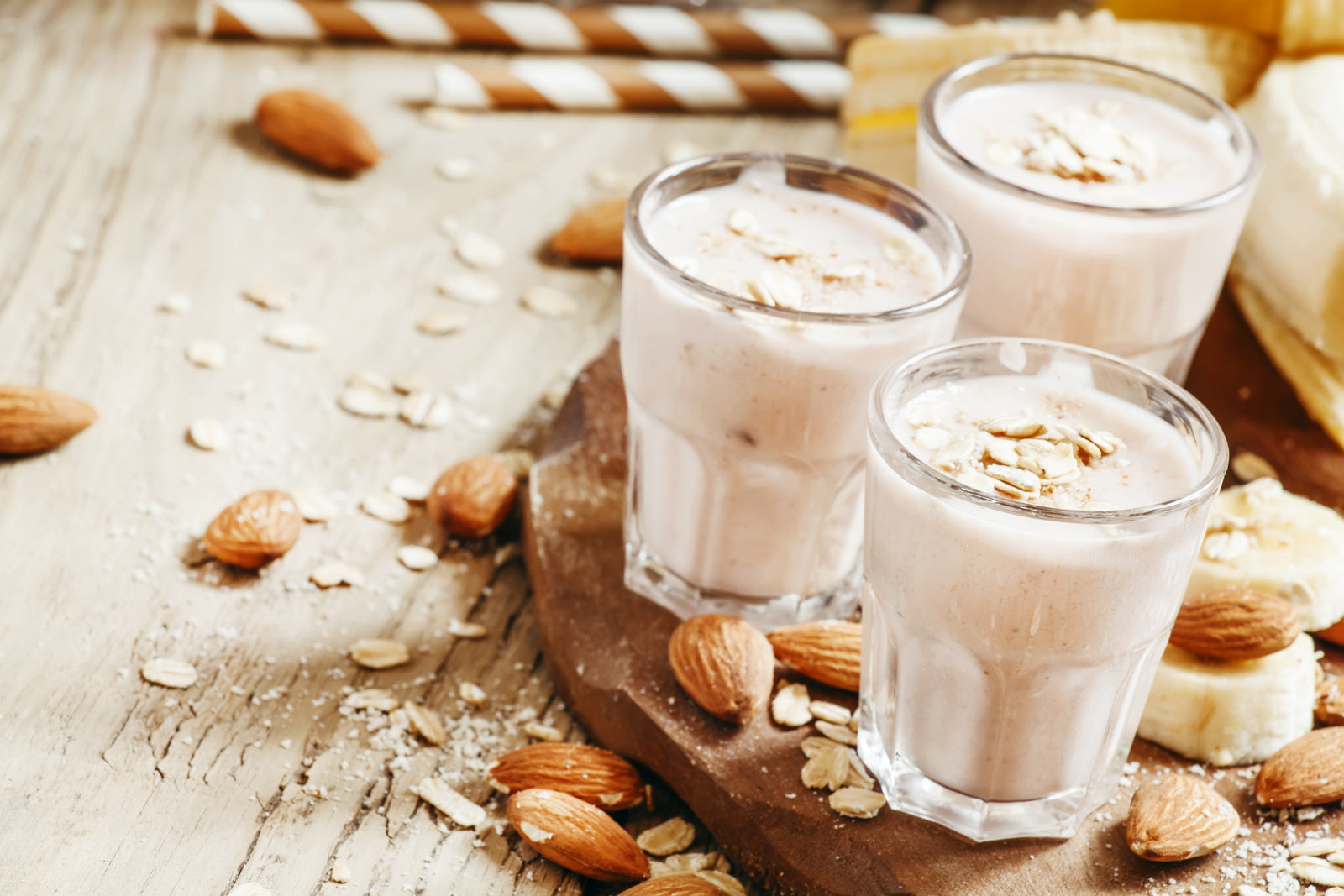 3 glasses of Almond Butter Proteini surrounded with almonds