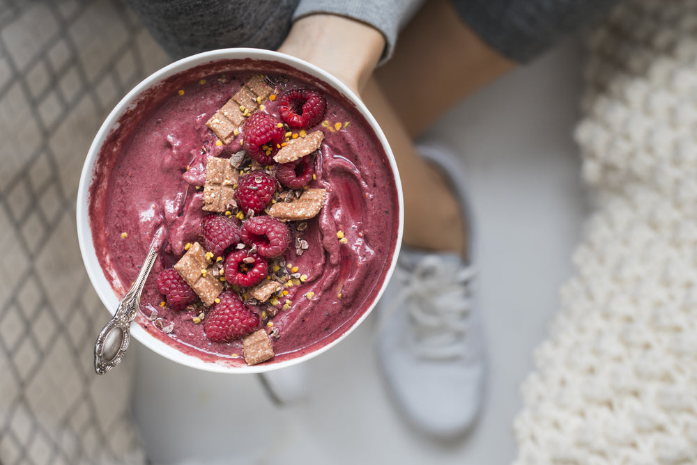 a bowl of chocolate almond butter berry smoothie with spoon, berries, and tart berries on top
