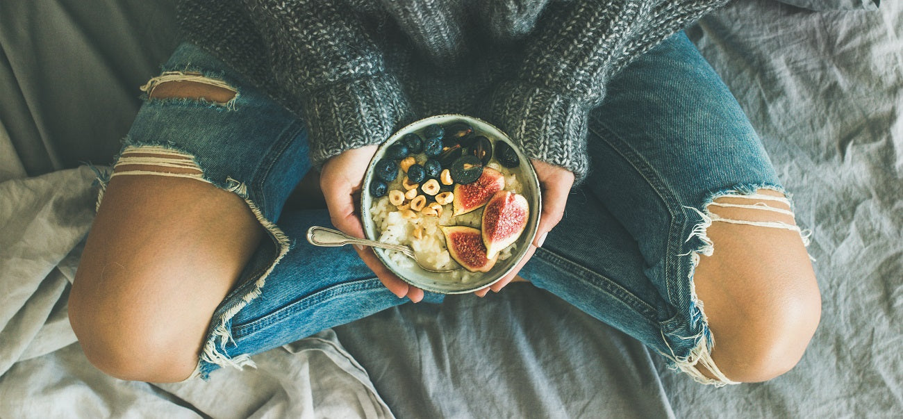 Woman sitting on the floor holding a healthy bowl of fruits